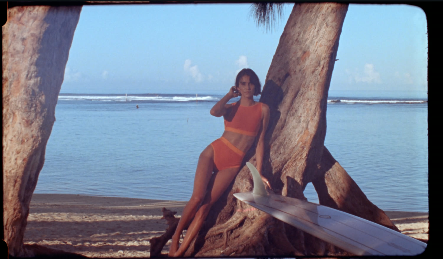 Image de film : surfeuse et planche sous les arbres